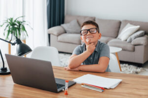 Little boy is having online lessons by using laptop at home